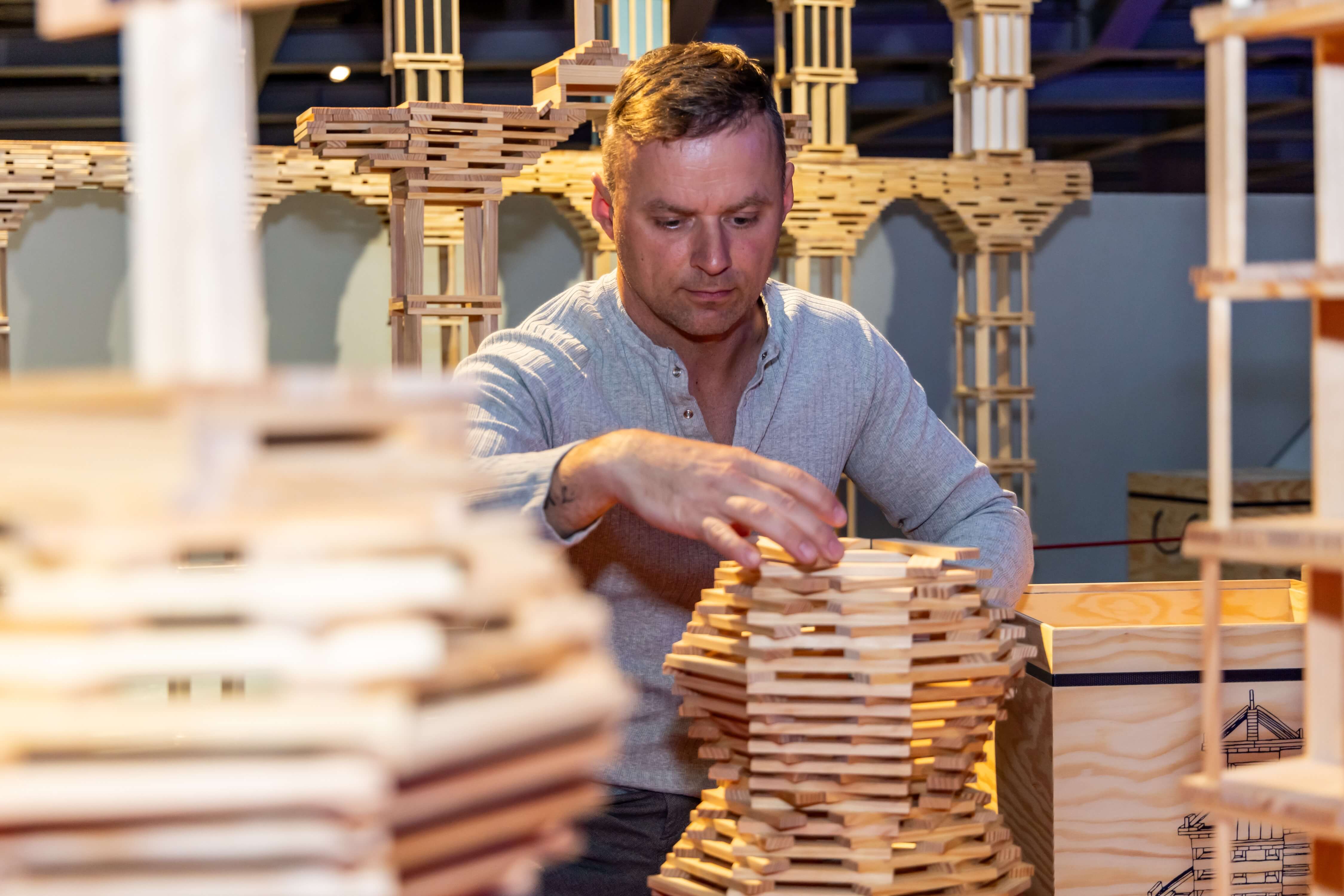 Mann stapelt Bausteine aus Holz