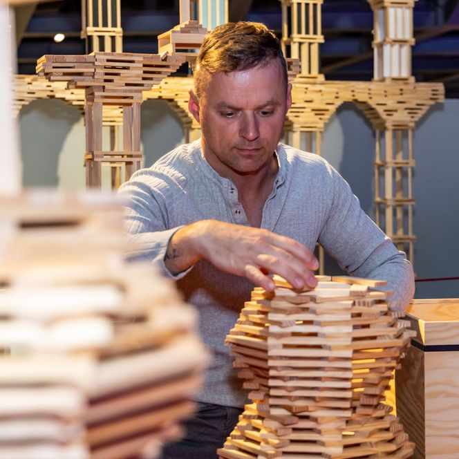 Mann stapelt Bausteine aus Holz