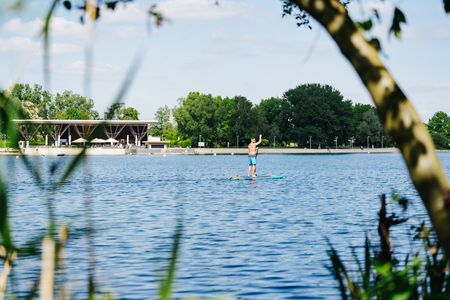 Ein SUP Fahrer auf dem Allersee, im Hintergrund der Kolumbianische Pavillon.