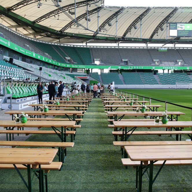 Mehrere Tische und Bänke auf dem Spielfeld eines Fußballstadions