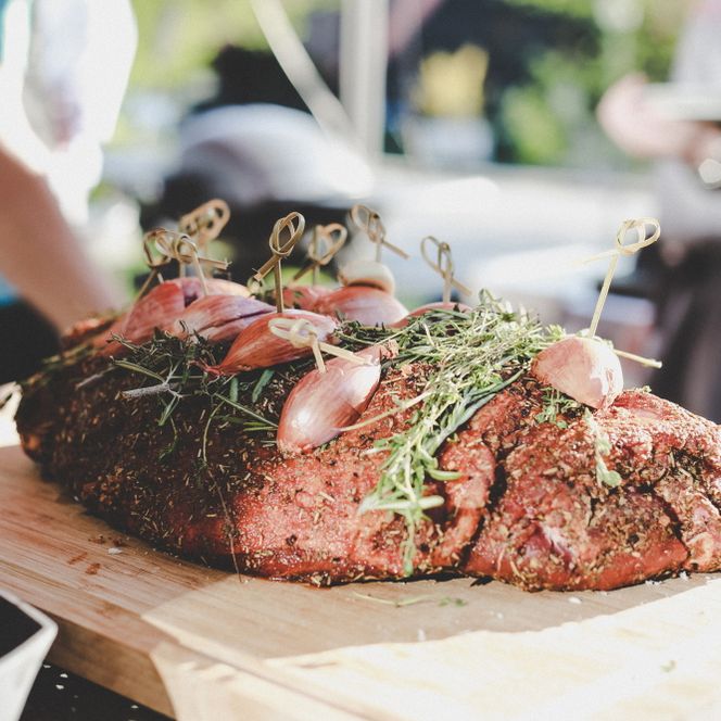 Ein gegrillter Braten mit Gewürzen darauf auf einem Holzbrett