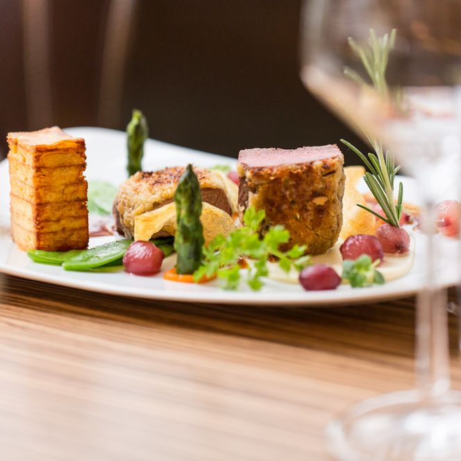 Ein Teller mit angerichteten Essen und ein Glas Wein