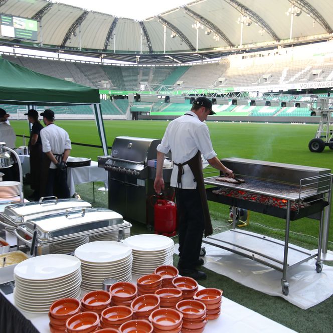 Ein aufgebautes Buffet mit  Grill auf dem Spielfeld eines Fußballstadions