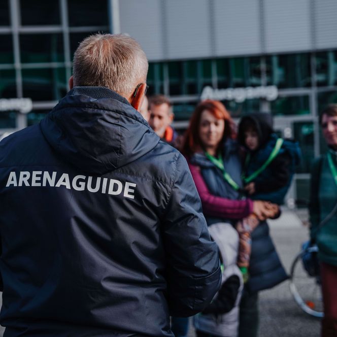 Eine Gruppe von Menschen steht vor einem Arenaguide